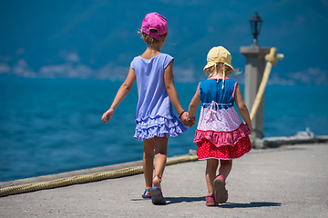 Image showing little sisters walking on the beach coast