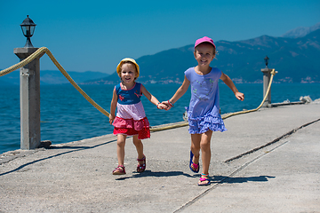 Image showing little sisters running on the beach coast