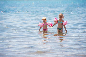 Image showing little girls with swimming armbands playing in shallow water