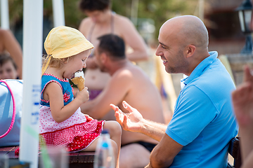 Image showing cute little girl eating ice cream with her young father