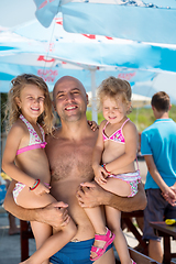 Image showing portrait of young happy father with daughters by the sea