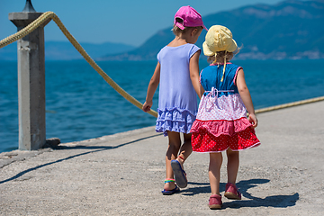 Image showing little sisters walking on the beach coast