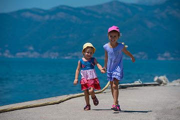 Image showing little sisters running on the beach coast