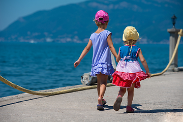 Image showing little sisters walking on the beach coast