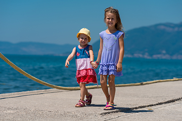 Image showing little sisters walking on the beach coast