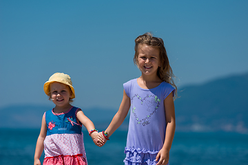 Image showing little sisters walking on the beach coast