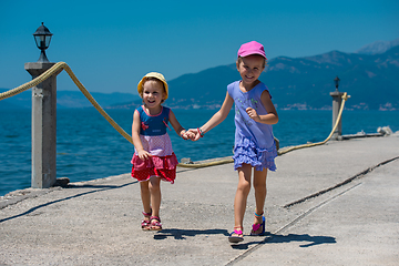 Image showing little sisters running on the beach coast