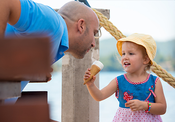 Image showing cute little girl eating ice cream with her young father