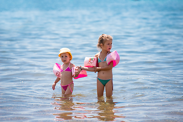 Image showing little girls with swimming armbands playing in shallow water