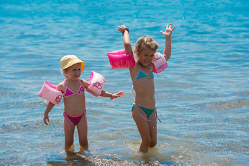 Image showing little girls with swimming armbands playing in shallow water