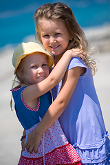 Image showing little sisters hugging on the beach coast