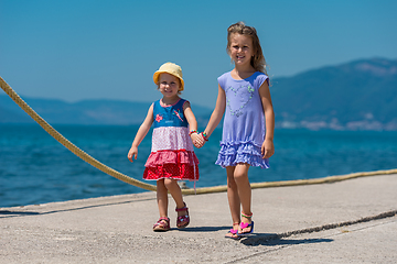 Image showing little sisters walking on the beach coast