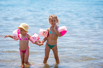 Image showing little girls with swimming armbands playing in shallow water