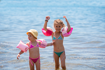 Image showing little girls with swimming armbands playing in shallow water