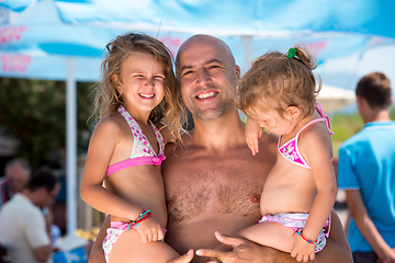 Image showing portrait of young happy father with daughters by the sea