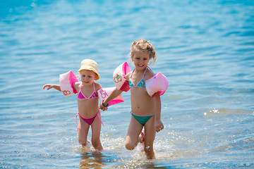 Image showing little girls with swimming armbands playing in shallow water