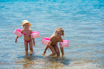 Image showing little girls with swimming armbands playing in shallow water