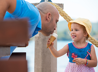 Image showing cute little girl eating ice cream with her young father