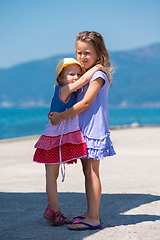 Image showing little sisters hugging on the beach coast