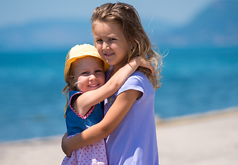 Image showing little sisters hugging on the beach coast