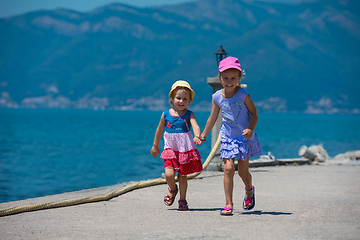 Image showing little sisters running on the beach coast