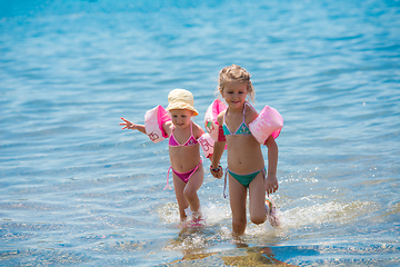 Image showing little girls with swimming armbands playing in shallow water