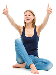 Image showing Young happy woman is showing thumb up sign