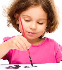 Image showing Little girl is painting with gouache