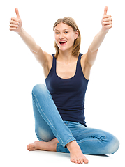 Image showing Young happy woman is showing thumb up sign