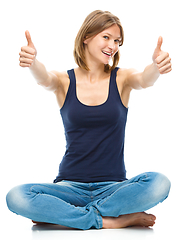 Image showing Young happy woman is showing thumb up sign