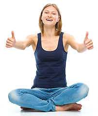 Image showing Young happy woman is showing thumb up sign