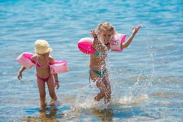 Image showing little girls with swimming armbands playing in shallow water