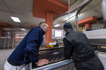 Image showing carpenters calculating and programming a cnc wood working machin