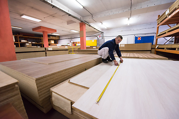 Image showing carpenter measuring wooden board