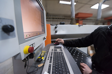 Image showing carpenters calculating and programming a cnc wood working machin