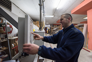 Image showing carpenter calculating and programming a cnc wood working machine