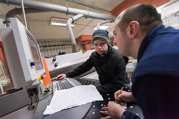 Image showing carpenters calculating and programming a cnc wood working machin