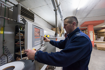 Image showing carpenter calculating and programming a cnc wood working machine