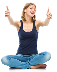 Image showing Young happy woman is showing thumb up sign