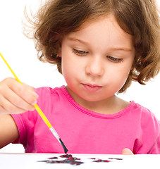 Image showing Little girl is painting with gouache