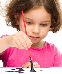 Image showing Little girl is painting with gouache