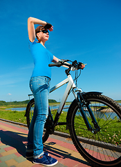 Image showing Young woman is standing in front of her bicycle