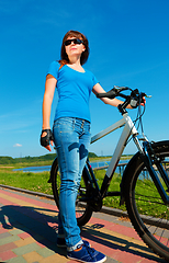 Image showing Young woman is standing in front of her bicycle