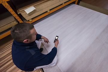 Image showing carpenter using a mobile phone to calculate measures