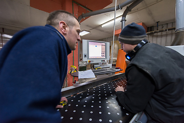 Image showing carpenters calculating and programming a cnc wood working machin