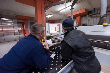 Image showing carpenters calculating and programming a cnc wood working machin