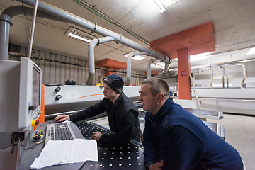 Image showing carpenters calculating and programming a cnc wood working machin