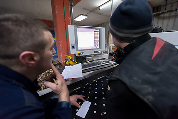 Image showing carpenters calculating and programming a cnc wood working machin