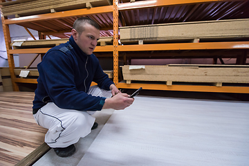 Image showing carpenter using a mobile phone to calculate measures