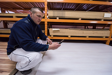 Image showing carpenter using a mobile phone to calculate measures